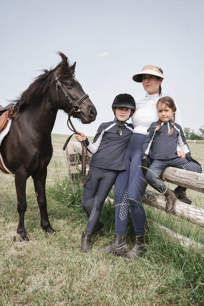 mom and daughters posing on a fence with a horse