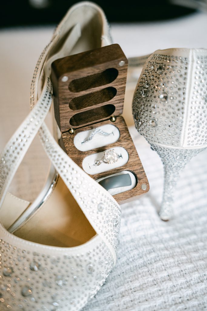 wedding rings in box on top of bride's shoes