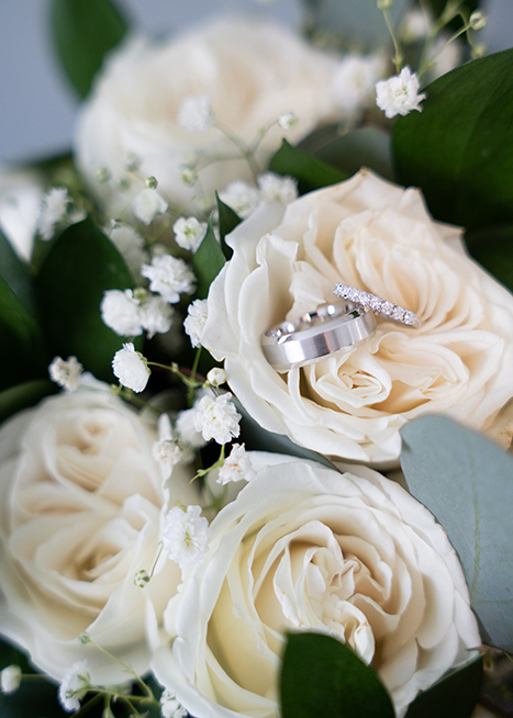 wedding rings resting on white flowers