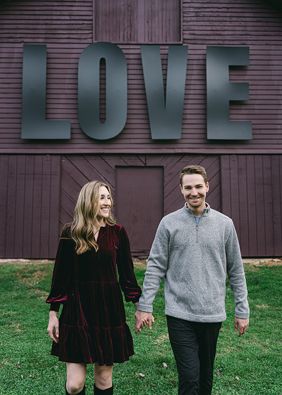 engaged couple in front of "Love" on a wall
