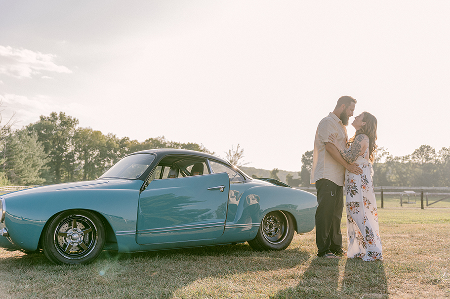 couple embracing behind classic car in sunset light