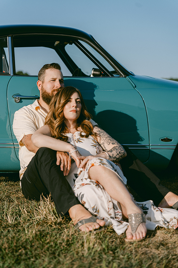couple leaning against classic car in bright sunlight