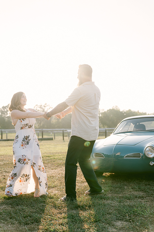 couple twirling in front of car